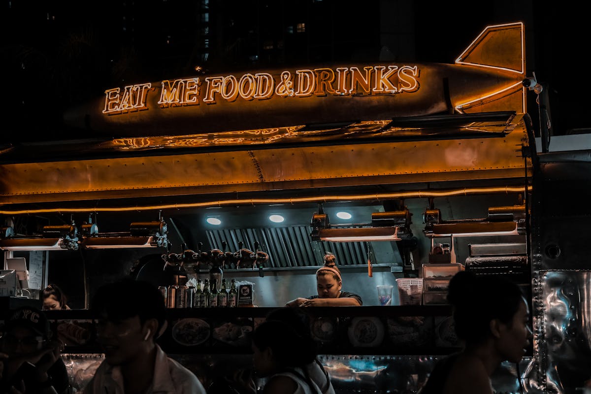 Food truck glowing at night with customers gathered around