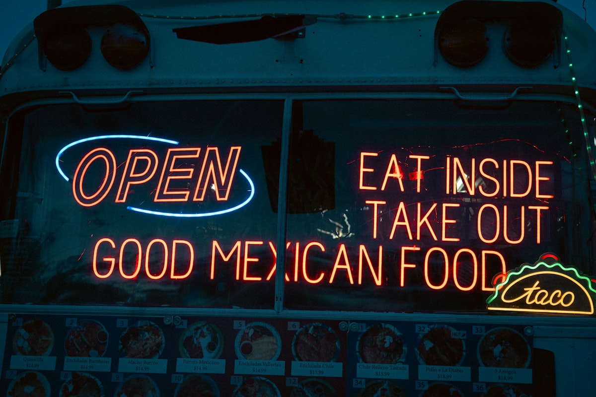 Stacked neon OPEN and Mexican Food signs at night