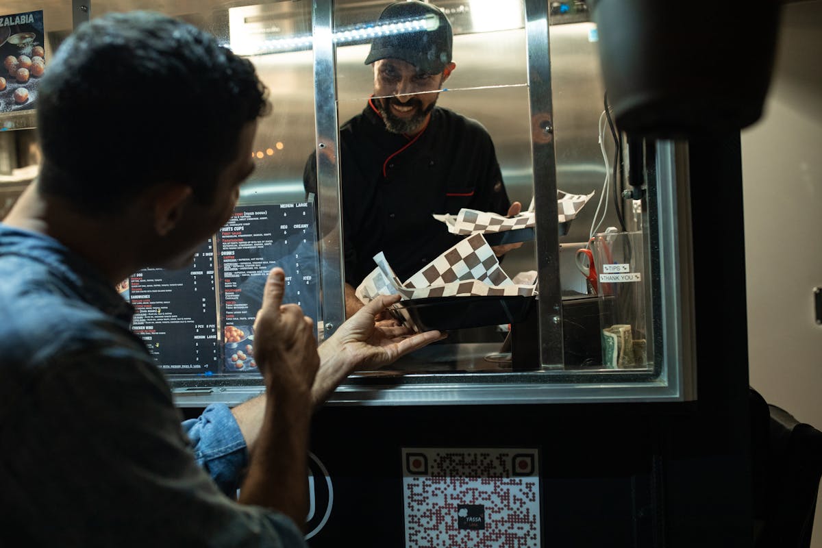 Customer ordering from chef inside food truck at night